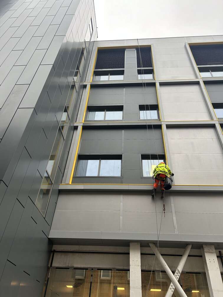 Avisan rope access technician performs cladding and cleaning on building