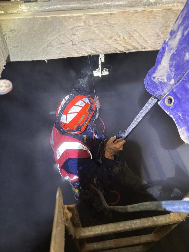 Avisan rope access technician wearing a helmet and holding a rope working in a confined space