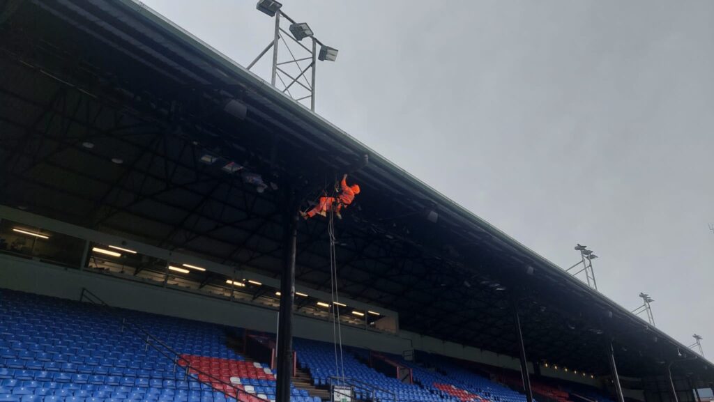 Avisan Rope access technician working on high level leak detection on stadium building