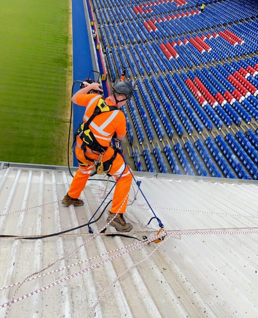 An Avisan rope access technician completing high level cleaning on stadium roof