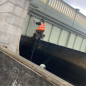 Man from industrial rope access company hanging from Rochester Bridge
