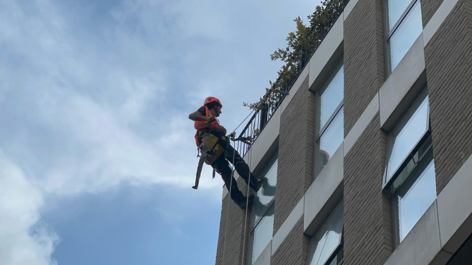 Avisan rope access technician using rope access solutions on a building for cleaning