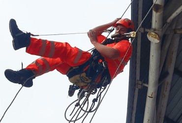Rope access Avisan rope access technician hanging from bridge in safety uniform