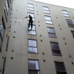 Avisan rope access technician hanging from rope on high building performing high level cleaning services