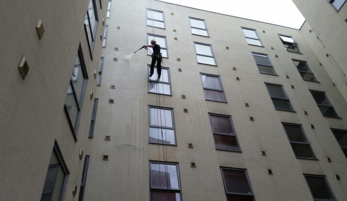 Avisan rope access technician hanging from rope on high building performing high level cleaning services