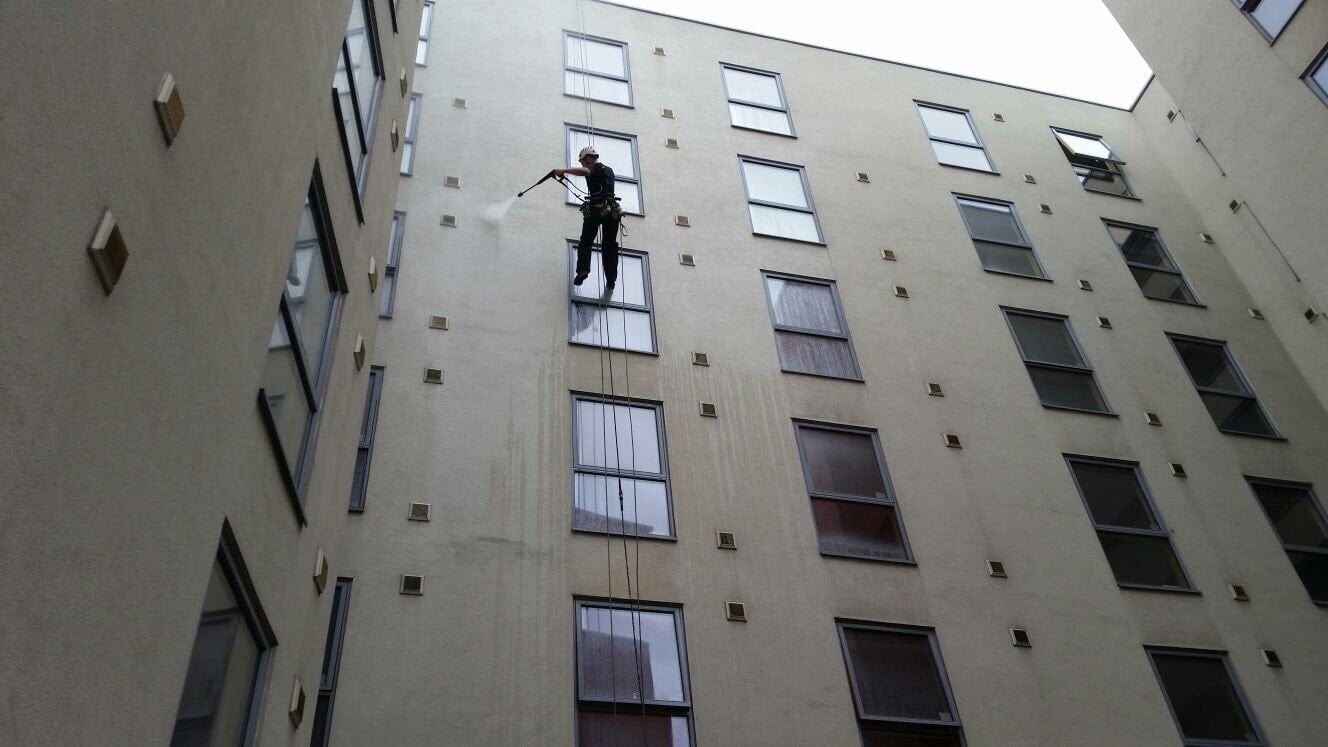 Avisan rope access technician hanging from rope on high building performing high level cleaning services