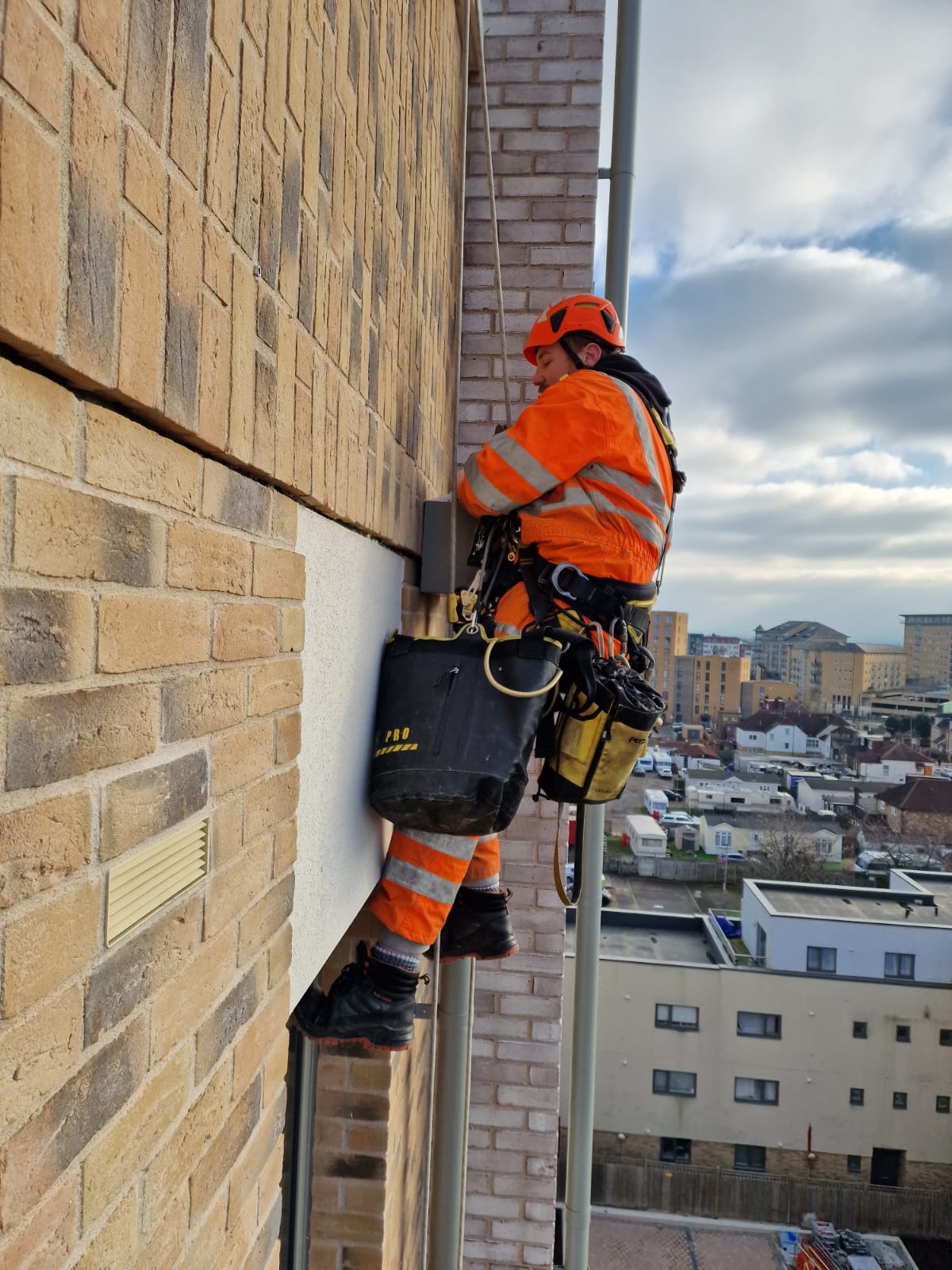 Rope technician from rope access company Avisan hanging by rope on exterior of tall building carrying out repairs