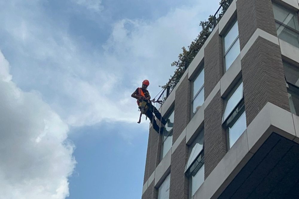 Rope access technician working on building